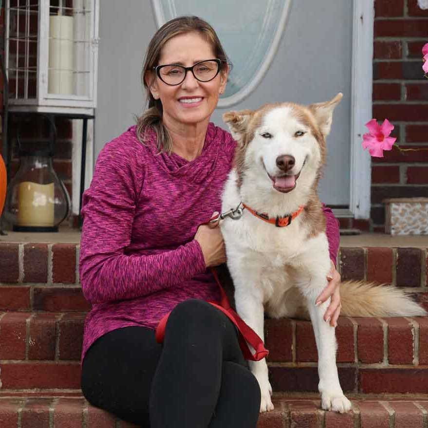 woman sitting on the porch with white and red colored husky